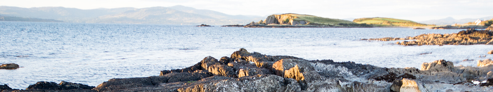 rocky coastline overlooking sea, land in distant horizon